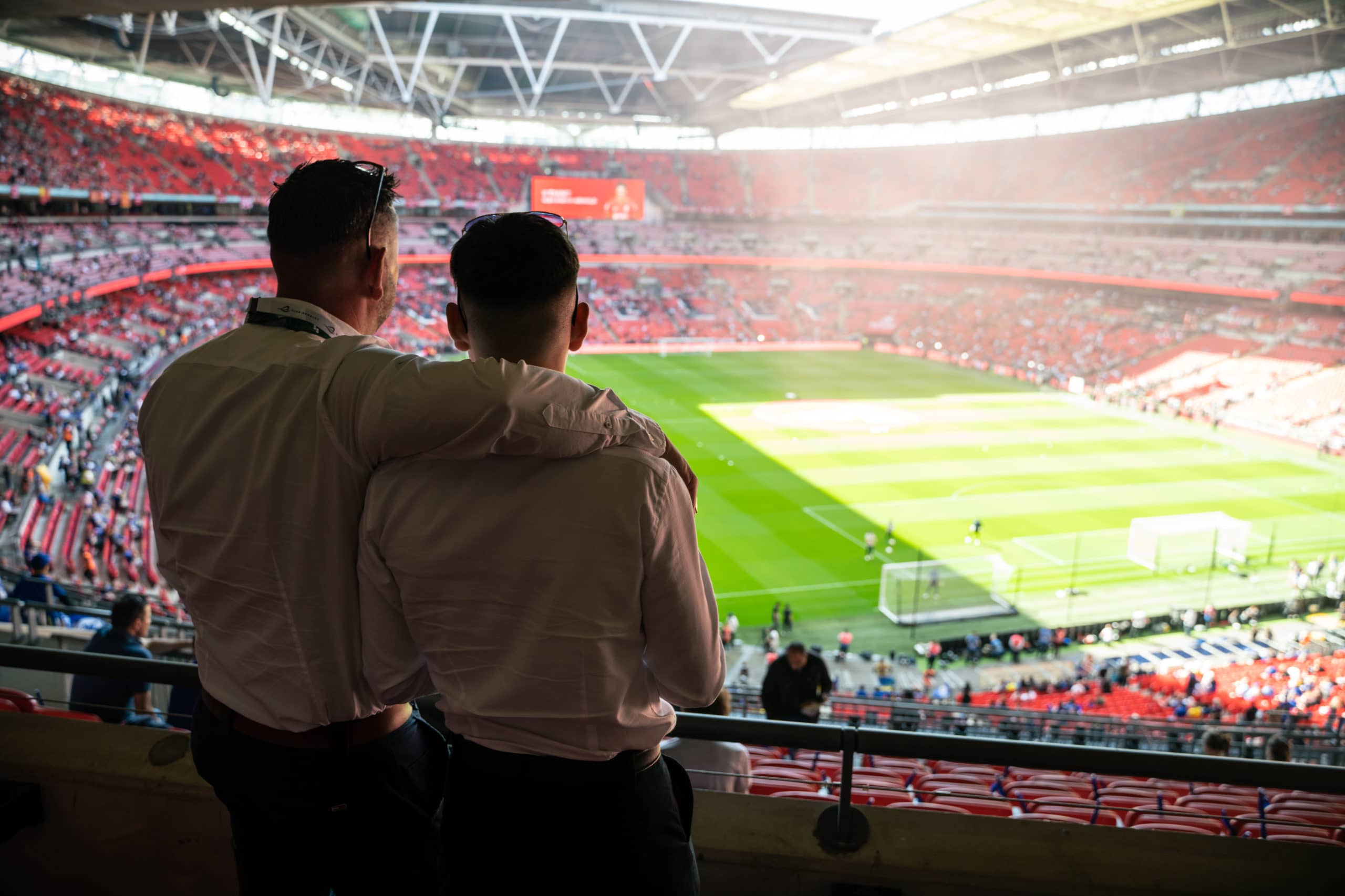 To fans med armene om hinanden ser ud over et fyldt stadion